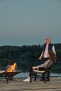 Couple watches the sunset sitting by the fire on the pier Royalty Free Stock Photo