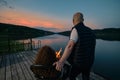 Couple watches the sunset sitting by the fire on the pier Royalty Free Stock Photo