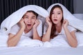 Couple watching scared movie under the blanket on bed