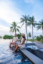 couple watching sunset in infinity pool on a luxury vacation in Thailand, man and woman watching sunset on the edge of a Royalty Free Stock Photo