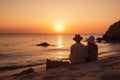 Couple watching sunset while sitting together on beach during summer tropical vacation Royalty Free Stock Photo