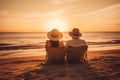 Couple watching sunset while sitting together on beach during summer tropical vacation Royalty Free Stock Photo