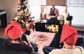 Couple watching tv on Christmas. Happy family holiday at home. Man and woman on couch relaxing with tree, decorations, lights. Royalty Free Stock Photo