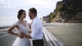 Couple on waterfront at rocks. Action. Newlyweds hugging on waterfront on background of rocks and sky. Bride and groom Royalty Free Stock Photo