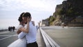 Couple on waterfront at rocks. Action. Newlyweds hugging on waterfront on background of rocks and sky. Bride and groom Royalty Free Stock Photo