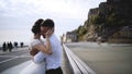 Couple on waterfront at rocks. Action. Newlyweds hugging on waterfront on background of rocks and sky. Bride and groom Royalty Free Stock Photo