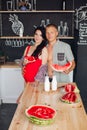 Couple with watermelon in the kitchen.They holding sliced watermelon at wooden table in modern kitchen. Royalty Free Stock Photo