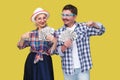 Couple of wealthy friends, adult man and woman in casual checkered shirt standing together holding fan of dollars and pointing Royalty Free Stock Photo