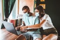 Couple wear a face mask for protecting the virus while working in a coffee shop with the laptop