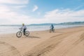 Couple wearing cycling helmets riding bicycles on the beach, California
