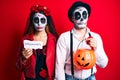 Couple wearing day of the dead costume holding pumpking and halloween paper depressed and worry for distress, crying angry and