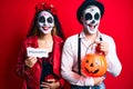 Couple wearing day of the dead costume holding pumpking and halloween paper smiling and laughing hard out loud because funny crazy