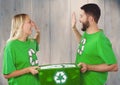 Couple wearing green recycling tshirts giving high five and holding box of recyclables