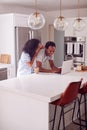 Couple Wearing Pyjamas Standing In Kitchen Working From Home On Laptop Royalty Free Stock Photo