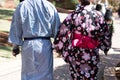 Couple wearing Yukata walking in a park holding hands on a sunny day