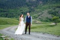 Couple in wedding attire with a bouquet of flowers and greenery is in the hands against the backdrop of the field at Royalty Free Stock Photo