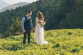 Couple in wedding attire with a bouquet of flowers and greenery is in the hands against the backdrop of the field at Royalty Free Stock Photo