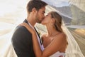 Couple, wedding and kissing with vail for love, compassion or affection together in nature. Married man kiss woman on