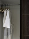 Couple of white clean bathrobes hanging on the wooden hangers on the rack. Royalty Free Stock Photo