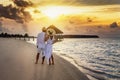 A couple in white clothes looks at the golden sunset on a tropical beach Royalty Free Stock Photo