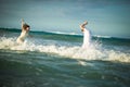 Couple in white clothes running in water on beach Royalty Free Stock Photo