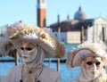 Couple in white masks with unrecognizable faces at Venice Carnival in Italy, with Basilica of St George Royalty Free Stock Photo