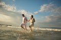 Couple in white running forward in water on beach Royalty Free Stock Photo