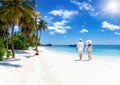 A couple in white summer clothing walks down a paradise beach Royalty Free Stock Photo