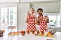 Couple of wife and husband cooking pastries at the kitchen afraid and terrified with fear expression stop gesture with hands,