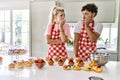 Couple of wife and husband cooking pastries at the kitchen looking stressed and nervous with hands on mouth biting nails