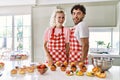 Couple of wife and husband cooking pastries at the kitchen winking looking at the camera with sexy expression, cheerful and happy Royalty Free Stock Photo