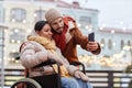 Couple with woman using wheelchair taking selfie photo outdoors in winter Royalty Free Stock Photo