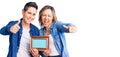 Couple of women holding empty frame approving doing positive gesture with hand, thumbs up smiling and happy for success Royalty Free Stock Photo