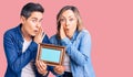 Couple of women holding empty frame hand on mouth telling secret rumor, whispering malicious talk conversation Royalty Free Stock Photo