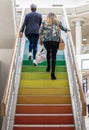 Couple of women shoppers walking up an LGBT Pride rainbow staircase