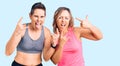 Couple of women wearing sportswear shouting with crazy expression doing rock symbol with hands up Royalty Free Stock Photo