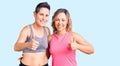 Couple of women wearing sportswear success sign doing positive gesture with hand, thumbs up smiling and happy Royalty Free Stock Photo