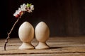 A couple of wooden Easter eggs among flowering cherry branches on a rustic table. symbolic composition of the spring holiday for a