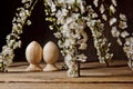 A couple of wooden Easter eggs among flowering cherry branches on a rustic table. symbolic composition of the spring holiday for a