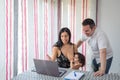 Couple works and watches laptop computer at home while baby takes mother`s breast Royalty Free Stock Photo