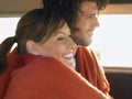 Couple wrapped in blanket in front seat of van profile head and shoulders