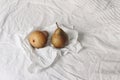 Couple of yellow pear fruit on crinckled wrapping paper. Autumn, summer breakfast in bed composition.White striped linen