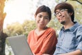 Couple young asian man and woman working with laptop and enjoying cheerful his online winner success  on a bench in the park Royalty Free Stock Photo