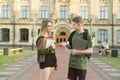 Couple of young attractive students talking outdoors in a park near the university buildong holding laptop, books and notebooks. Royalty Free Stock Photo