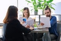 Couple of young clients at meeting with agent insurer realtor, reading paper contract