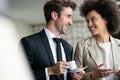 Couple of young colleagues in formal wear standing at workplace, drinking coffee near window Royalty Free Stock Photo