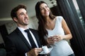 Couple of young colleagues in formal wear standing at workplace, drinking coffee near window Royalty Free Stock Photo