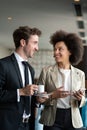 Couple of young colleagues in formal wear standing at workplace, drinking coffee near window Royalty Free Stock Photo