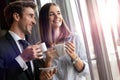 Couple of young colleagues in formal wear standing at workplace, drinking coffee near window Royalty Free Stock Photo