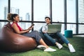 Couple of young designers working at modern office, two coworkers discussing fun project over a laptop, little team of Royalty Free Stock Photo